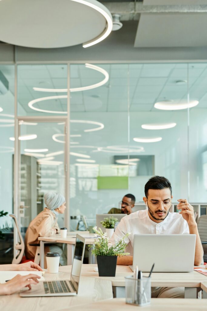 Diverse team working in a modern office with laptops and natural light.